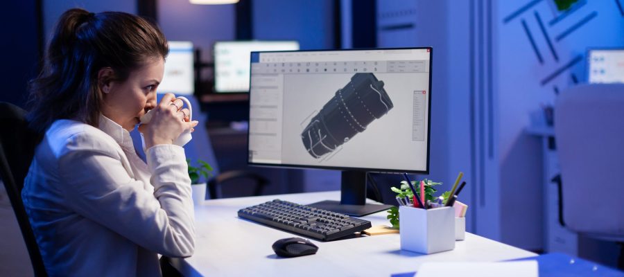 Woman engineer working late at night on 3D model of industrial turbine while drinking coffee in front of computer. Workaholic freelancer studying prototype design on pc showing cad software on device display